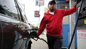 A man pumps gas into a car at a gas station.