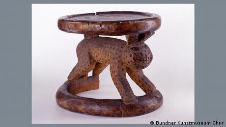 A wooden stool with a human-leopard like figure carved as its legs