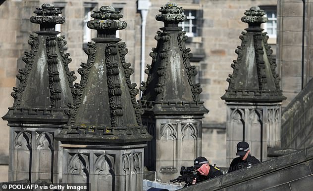 A police officer looks through the sight of a sniper rifle from the roof of St Giles' Cathedral in Edinburgh on Tuesday, where Queen Elizabeth II is lying at rest