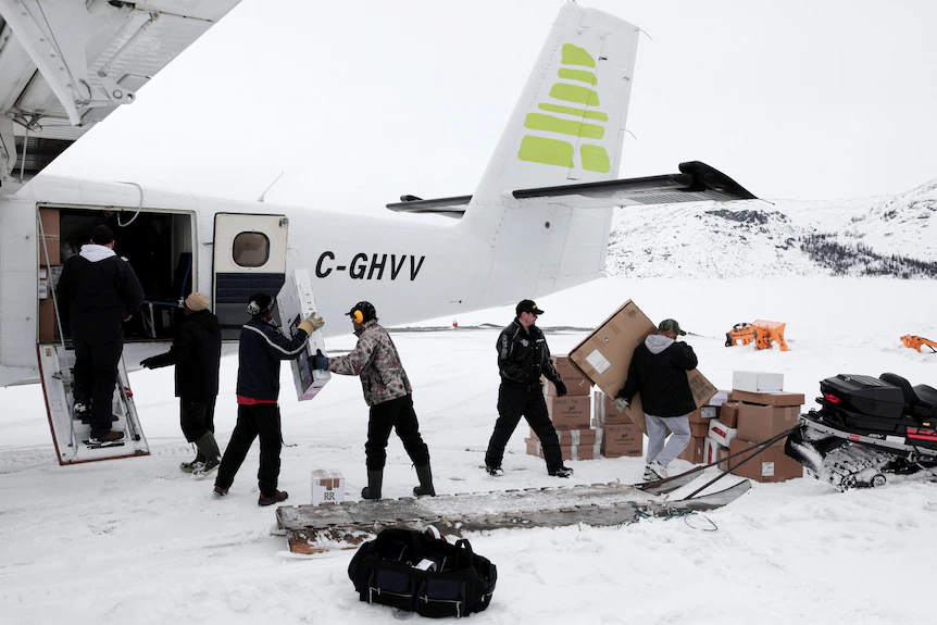 People are seen forming a chain while loading up boxes into a small airplane.