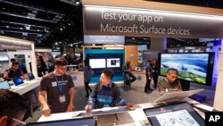 FILE - Workers demonstrate Microsoft Surface devices at the Microsoft Build 2017 developers conference, May 10, 2017, in Seattle.