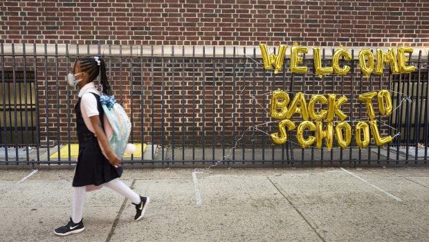 A girl passes a "Welcome Back to School" sign as she arrives for the first day of class at Brooklyn's PS 245 elementary school, Monday, Sept. 13, 2021, in New York