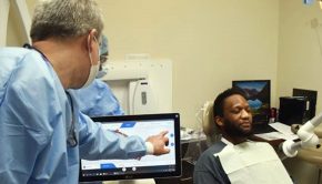 Dentist indicating dental process on computer screen