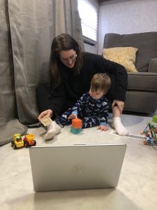 a mom and child sitting on the floor looking at a laptop