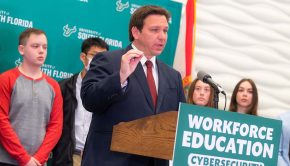 Governor Ron DeSantis stands at the podium surrounded by students