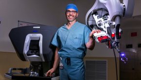 Dr. Garrett Friedman poses for a photo with a da Vinci SP surgical robot in an operating room o ...