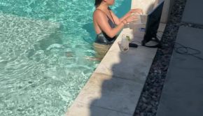 Woman Relaxingly Works on Computer While Standing Inside Swimming Pool